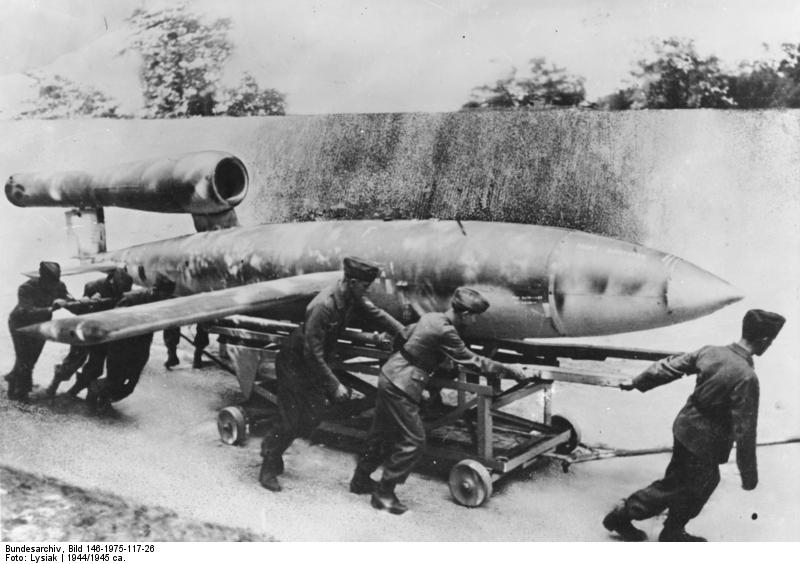 V1 vor dem Start Aus guter Deckung wird "V1" an die Abschußstelle gerollt. Der Start erfolgt durch eine Pressluftanlage. Mit Hilfe eines Fernlenkverfahrens trifft die "V1" das befohlene Ziel. Die gleichbleibend hohe Geschwindigkeit, die von keinem Feindjäger erreicht wird, erhält "V1" von einem Raketenantrieb. Diese erste deutsche Vergeltungswaffe ist eine hervorragende Schöpfung unserer Luftrüstung. Foto: PK-Lysiak/Transocean-Europapress